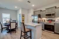 Stock photo showing kitchen with working/serving island, breakfast area, pantry and laundry in back corner.