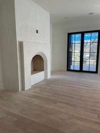 During construction photos: Living Room with close up view of gas fireplace and steel doors to back porch.