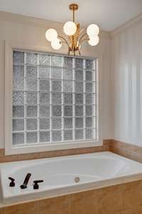 The art deco chandelier over the jacuzzi tub is a perfect compliment to the subtly stripped wallpaper.