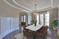 Notice the curvature in the wall adjacent to the staircase giving this dining room a striking visual statement. The arched entries and triple doors leading to the balcony further elevates the feel of the space. *This photo has been virtually staged.