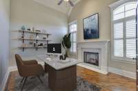 A gorgeous office setting. Enjoy the warmth and glow of this fireplace during the cold months and the ongoing aesthetic in the warm months. Double glass-paned doors and vaulted ceilings lend an open feel. *This photo has been virtually staged.