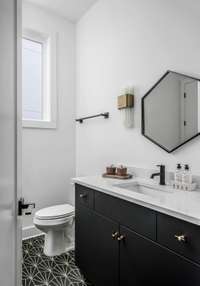 Step into the property's first bathroom, graced with geometric accents throughout to catch the eye with dynamic angular sensibility. Ample storage below the vanity accommodates toiletries and other sundries for your guests' convenience.