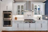 The kitchen features double ovens, 6 burner gas range, pot filler, stainless hood and glass front cabinets.