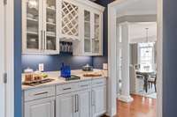 The Butler's Pantry is lovely with white cabinets, quarts countertops, under cabinet lights, and glass front cabinets.