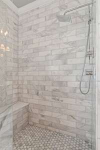 Marble shower with bench and frameless shower door.