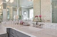 Calcutta marble countertops, undermount sinks and sconces grace each of the two vanities.