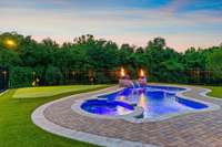 The heated 15x35 ft pool w/ spillover spa and lights, featuring copper water/fire bowls, surrounded by Belgard pavers and maintenance free synthetic turf and putting green.