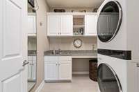 The main floor laundry room has white cabinets, granite countertops, and a great folding area.