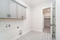 Spacious laundry room with custom tile and upper cabinets