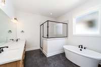 Primary bathroom features double vanities, tiled shower, tile. floors  and stand alone tub