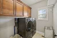 Laundry Room On Main Level With Built In Cabinets And Tile Flooring