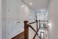 The Upstairs Hallway leads towards Secondary Bedrooms, Family Room and an Open Area which functions well as a Rec Room extension or Home Office/Library Loft. Double Linen Closet with Custom Wood Shelving to the left.