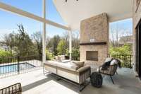 Covered back porch with blue stone flooring has a wood burning fireplace with gas starter