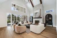 Lovely, light and bright open concept living room with vaulted ceilings, stained beams, and wood burning fireplace gas starter finished off with stone to the ceiling