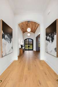 Beautiful curved arches in the entryway lead to a perfectly located gallery wall with artwork uplights in the floor