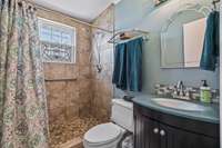 The hall bathroom has a recently remodeled tile shower!  The vanity in this bathroom is unique in color and style!