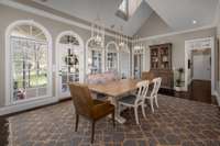 This beautiful extra dining space with stylish pendant lighting is flooded with natural light all times of the day from skylight & wall-to-wall arched windows! A french door leads to the large covered back patio, allowing for seamless entertaining.