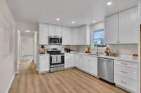 Spacious kitchen with custom cabinets, stainless steel appliances and quartz countertops.