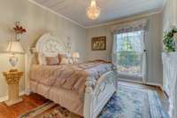 The elegant 2nd bedroom on the main floor features hardwood flooring, a ten-foot ceiling, a crystal light fixture, reclaimed- wood paneling, and a walk-in closet.