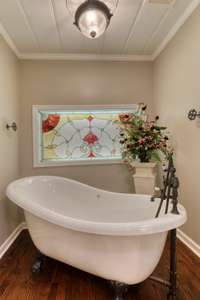 Another view of the claw-foot tub with antique-inspired fixtures and decor accents.