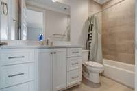 The bathroom for bedroom four features tile to the ceiling in the shower / tub combo, shaker style cabinetry, and an undermount sink