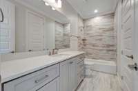 The bathroom for bedroom five features tile to the ceiling in the shower / tub combo, shaker style cabinets, and an undermount sink