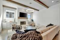 The living area is effortlessly chic, with ceiling beams contributing to a cozy and relaxing gathering space.  *The pictured chandelier does not convey with the home.