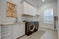 The laundry room features a practical layout with cabinetry to maximize storage space