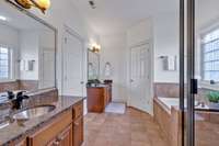 This thoughtfully designed owner's bath features tile floors, separate vanities, a Jacuzzi tub with tile surround, a walk-in tiled shower, and a separate water closet for added privacy.