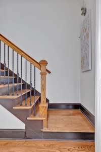 A captivating centerpiece in the main living room is undoubtedly the staircase, boasting hardwood stairs, painted risers, elegant iron balusters, and a striking hardwood landing.