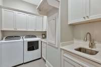 Laundry room has ample storage, sink, and laundry chute