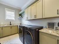 Spacious laundry room with storage, utility sink, and cabinets