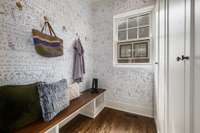 Mudroom just inside the back door with hooks for hanging, bench for seating and custom cabinetry for storage