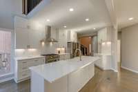 Open concept kitchen in white showcasing a white and brass themed design, a white quartz  island. This kitchen is an updated and timeless look.