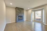 Renvovated Den with Tiled Gas fireplace, solid white oak wood floors, recessed lights, and a bay-window.