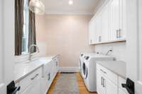 Custom cabinetry graces the walls, providing not only ample storage but also adding a touch of sophistication to the laundry room.