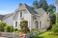 Accentuating the cottage's exterior are crisp white shutters adorning the windows, contrasting beautifully against the gentle exterior palette.