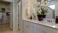 Double sinks, quartz countertops and the adjacent walk-in closet keeps the space organized *Photo is of similar decorated model