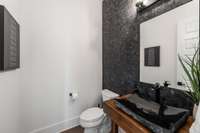 Powder room downstairs, with rock wall feature and custom pedestal and stone sink.