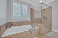 Separate, jetted soaking tub and glass, tiled shower.