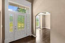 A stunningly gorgeous front door with sidelights and a transom window create a vibe of elegance and style. Note the beauty of the leaded glass detail and natural light flowing through into the home. Note the NEW 3/4" hardwood floors!