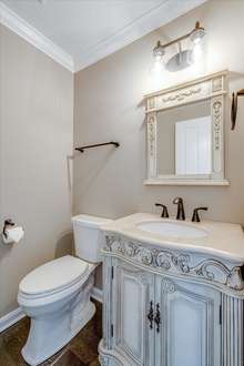 Downstairs you will find a most convenient half bath/powder room for yourself and your guests. The intricate detailing on the single vanity and mirror make this room extra special!