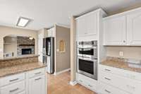 Freshly painted white cabinetry, granite countertops (w/half bullnose edge), new light fixtures and beautiful tile flooring complete the kitchen and dining area -- so pretty! Notice the custom tiled niche areas on the walls as you enter the kitchen!