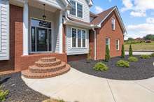 A newly installed, curved concrete sidewalk leads to this beautiful front entry. Stylish brick steps, new landscaping and fresh mulch make for a warm and welcoming entry!