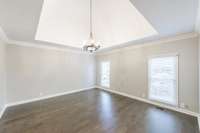 The oversized primary bedroom on the main level features a barrel ceiling design, and new wood floors