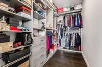 The incredible primary closet is generously sized and outfitted with an efficient mix of custom shelving, drawers, and ample hanging space