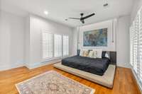 Windows with plantation shutters, inset lighting, hardwood floors, and the perfect size makes this primary bedroom a 10!