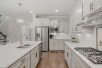 Gas cooktop with neutral custom tile backsplash Look at these gorgeous countertops!