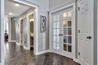 View down the right side of the entry showcasing the beautiful newer hardwood floors, a coat closet and glass double doors to the study.  Notice all of the beautiful millwork.