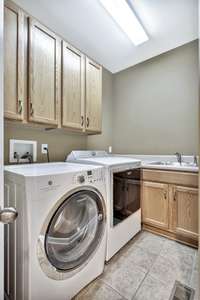 A dedicated laundry room with tile floors and custom cabinetry for plenty of storage is located down the hall from the kitchen on the first floor.